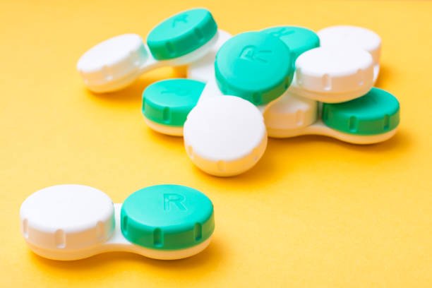 A pile of containers for storing contact lenses on a yellow background